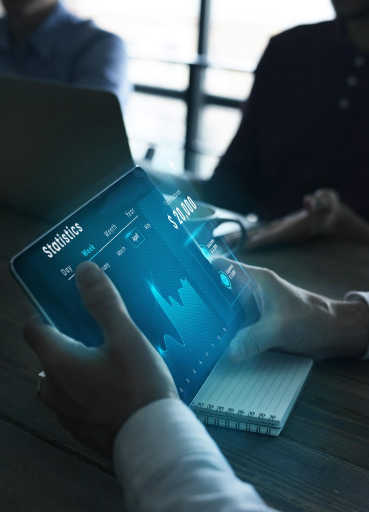 Photo of a person holding a tablet showing statistics on a graph.